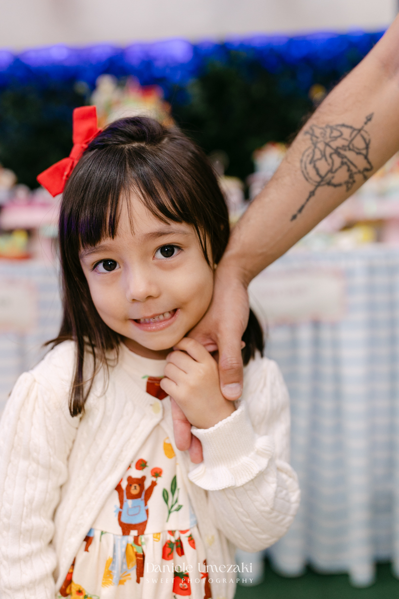 Maya sorrindo em frente à decoração de feira criada pela Panda Pink durante seu aniversário de 4 anos no Buffet Santa Arruaça, em Arujá.