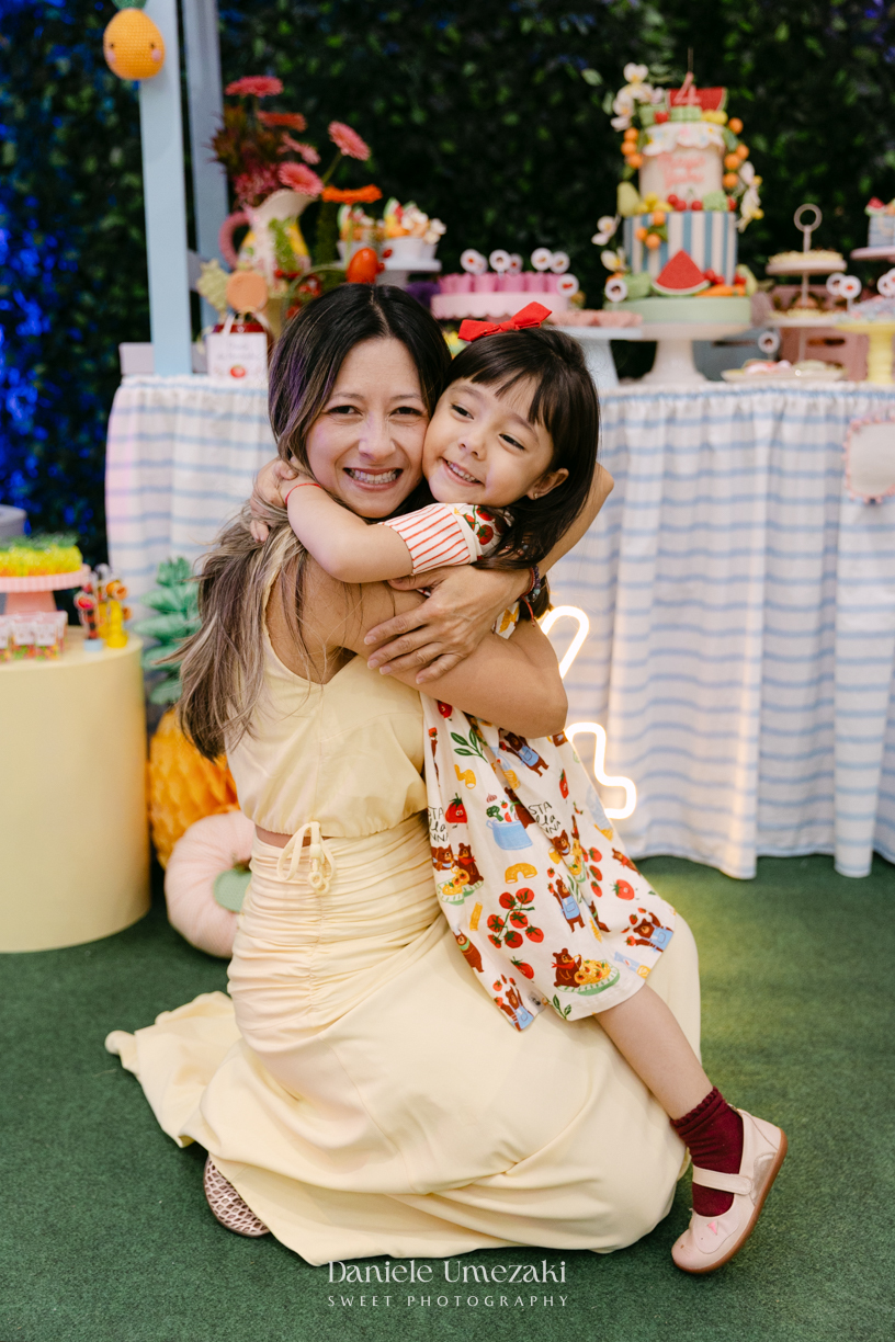 Maya sorrindo em frente à decoração de feira criada pela Panda Pink durante seu aniversário de 4 anos no Buffet Santa Arruaça, em Arujá.