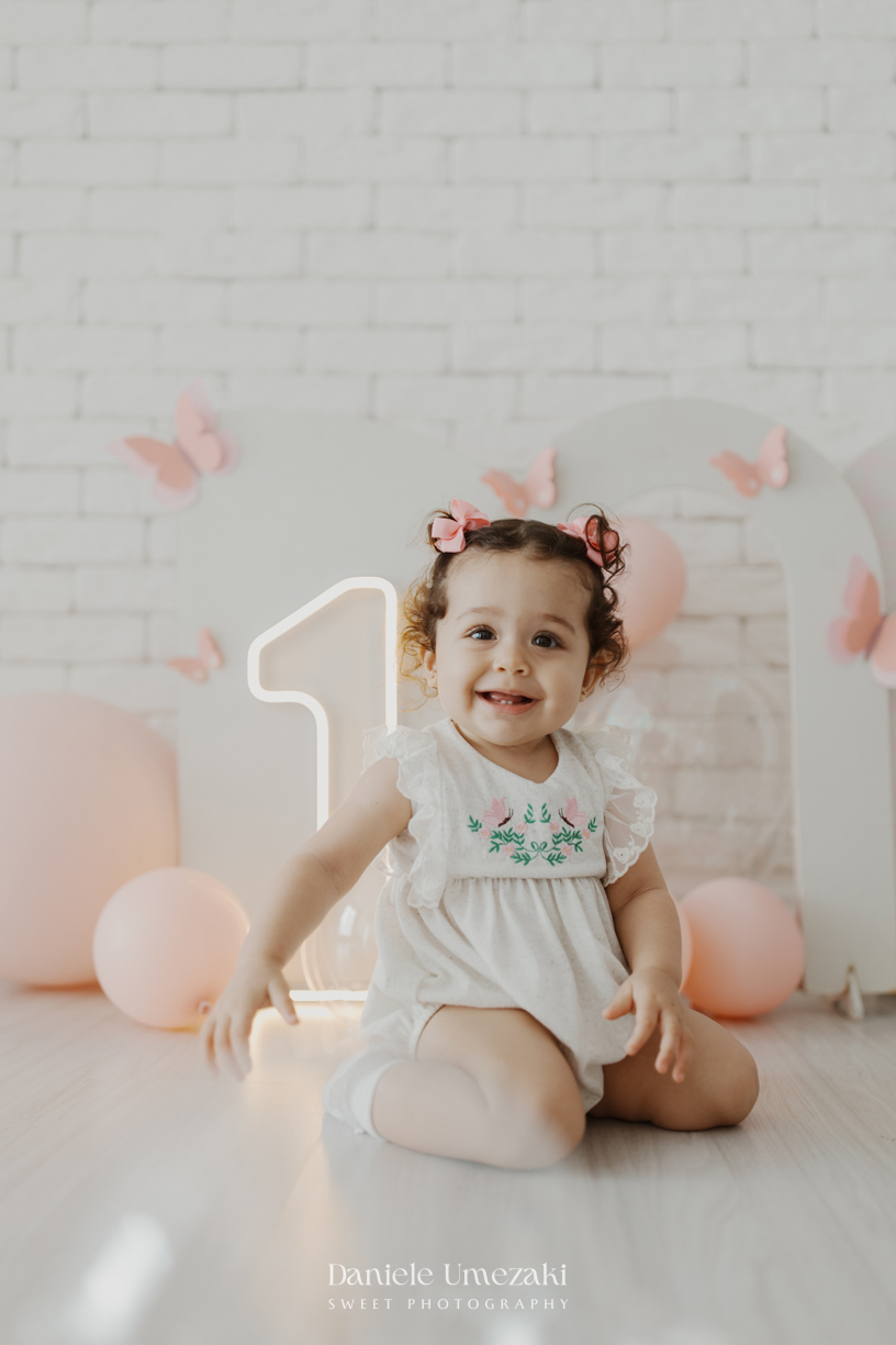 Sofia durante ensaio de 1 ano em estúdio com cenário clean e minimalista em Mogi das Cruzes, fotografada por Dani Umezaki.