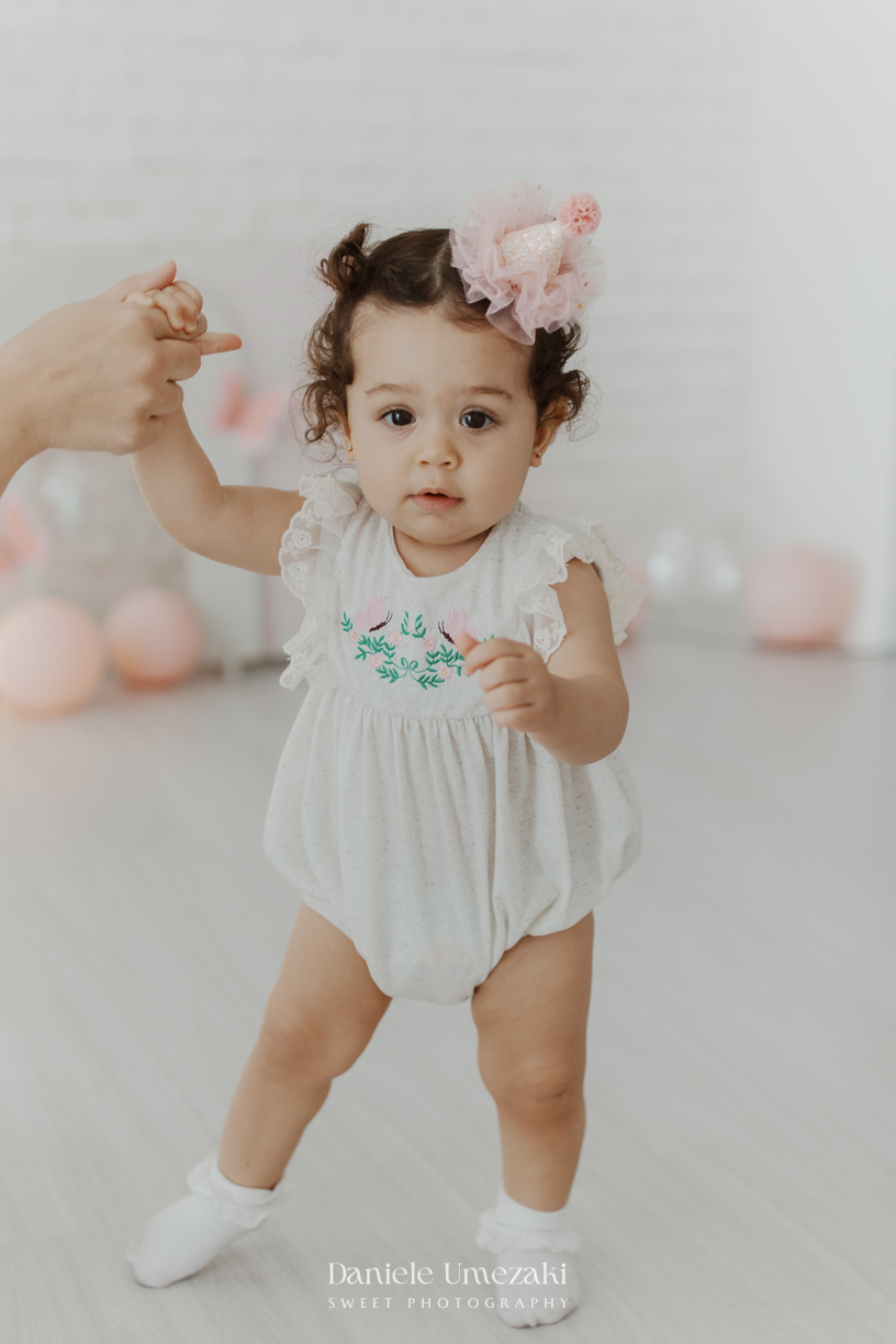 Sofia durante ensaio de 1 ano em estúdio com cenário clean e minimalista em Mogi das Cruzes, fotografada por Dani Umezaki.