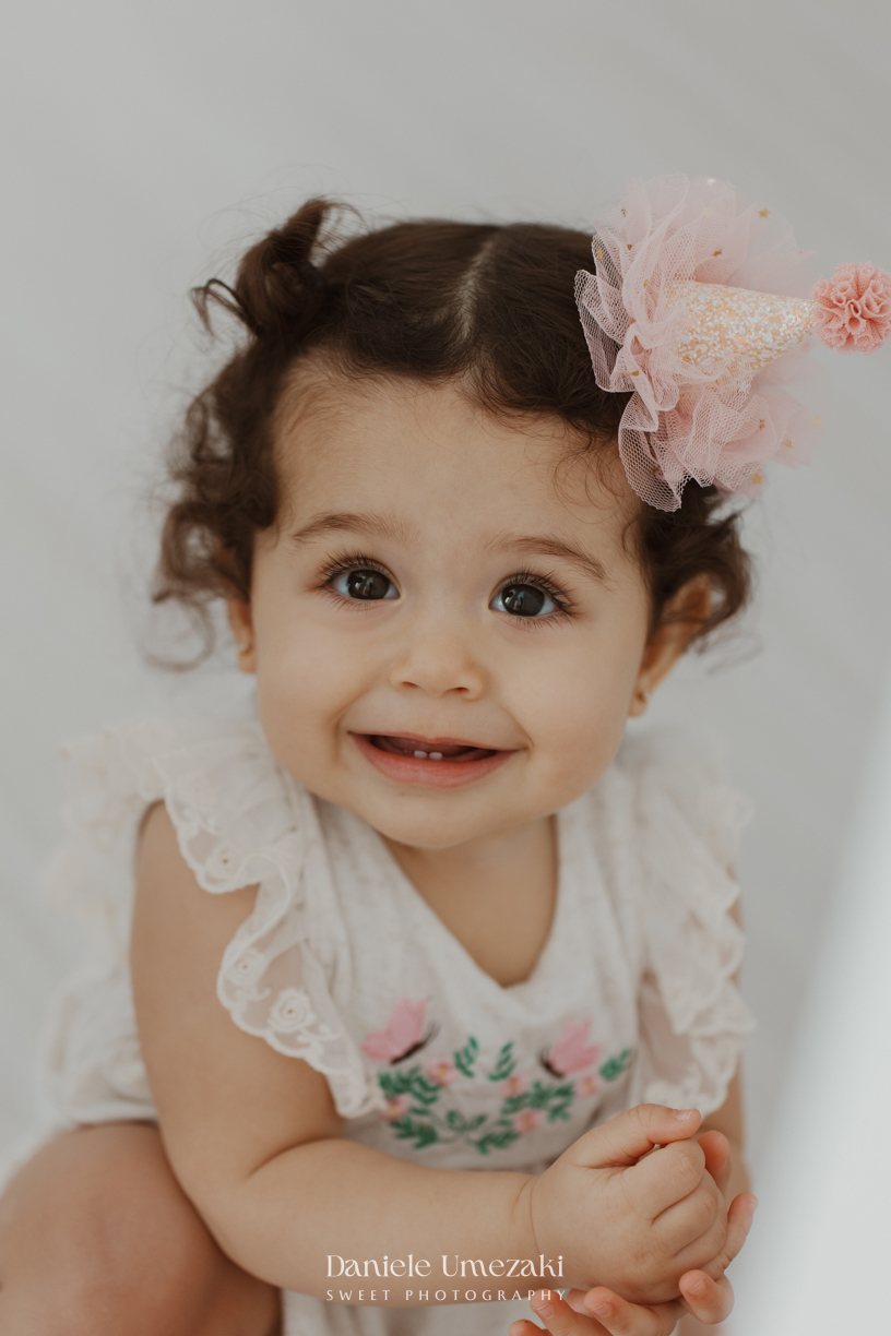 Sofia durante ensaio de 1 ano em estúdio com cenário clean e minimalista em Mogi das Cruzes, fotografada por Dani Umezaki.