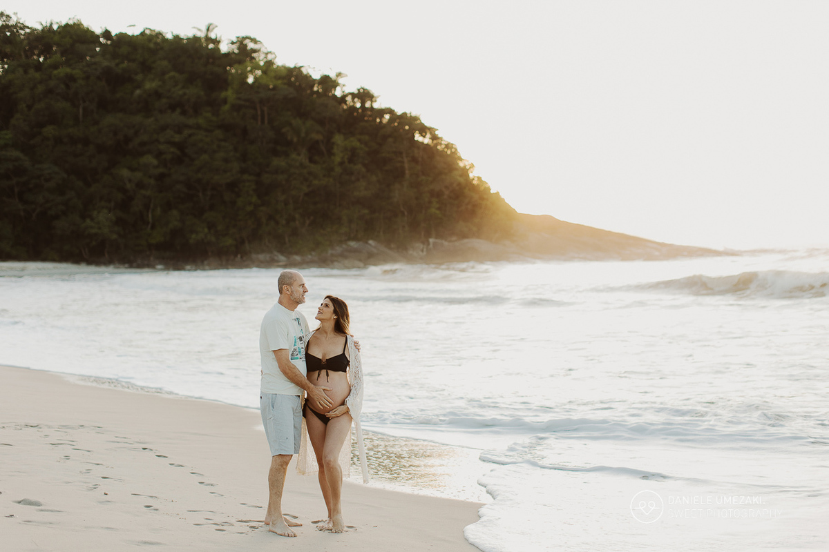 Iris e Antonio Carlos durante ensaio gestante na praia ao nascer do sol, esperando a chegada da pequena Carolina