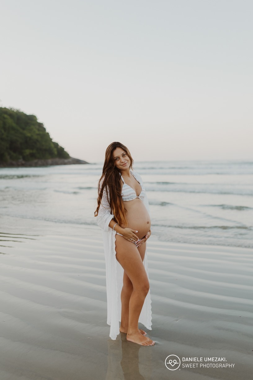 Gestante com a família durante ensaio fotográfico na praia ao nascer do sol