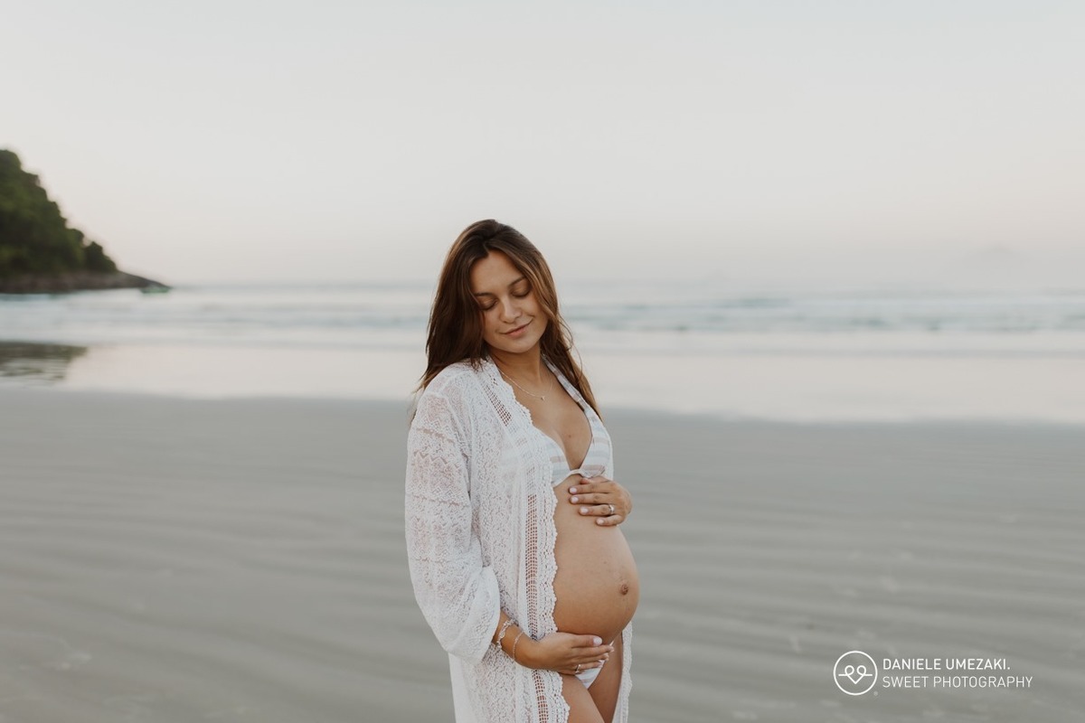 Gestante com a família durante ensaio fotográfico na praia ao nascer do sol
