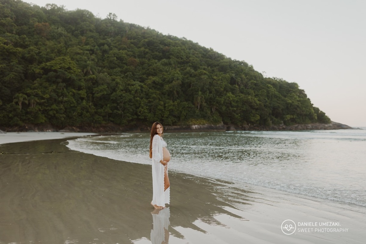 Gestante com a família durante ensaio fotográfico na praia ao nascer do sol