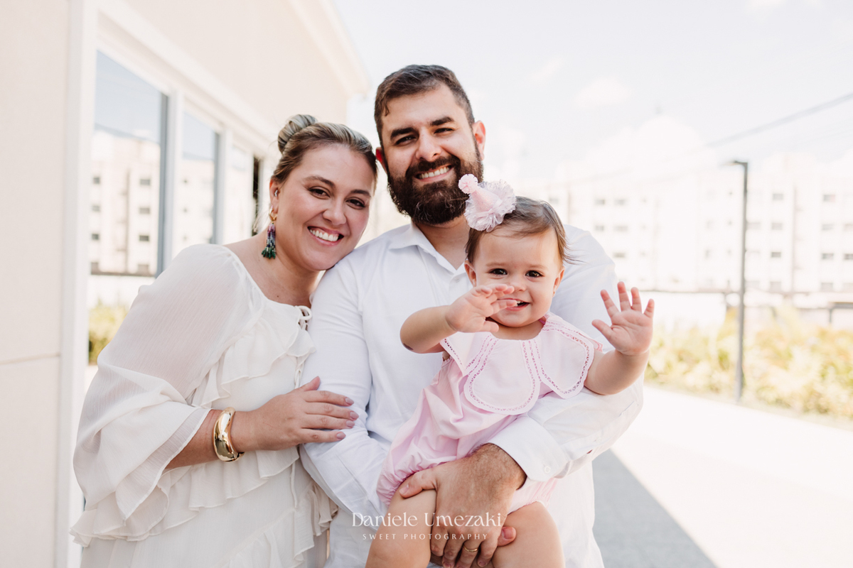 Fotografia dos pais com a Olivia durante a comemoração do seu primeiro aninho.