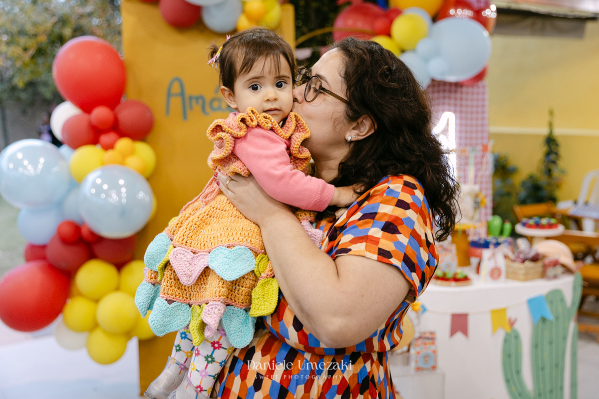 Amália comemorando seu primeiro aniversário em uma delicada festa junina no Quintal Pitangueiras, em Mogi das Cruzes, cercada pela família e amigos.