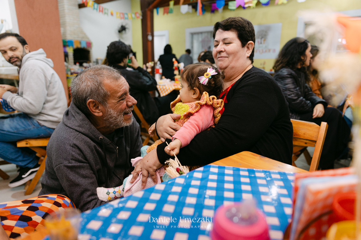 Amália comemorando seu primeiro aniversário em uma delicada festa junina no Quintal Pitangueiras, em Mogi das Cruzes, cercada pela família e amigos.