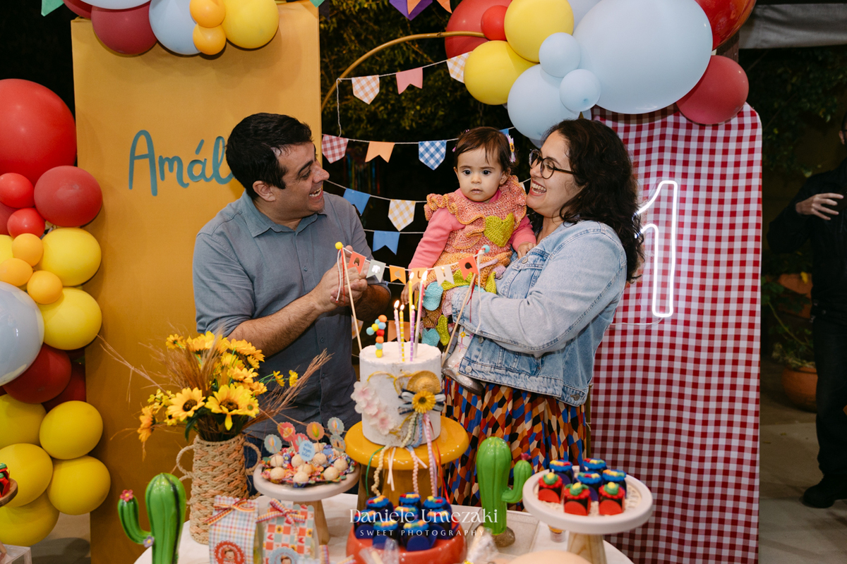 Amália comemorando seu primeiro aniversário em uma delicada festa junina no Quintal Pitangueiras, em Mogi das Cruzes, cercada pela família e amigos.