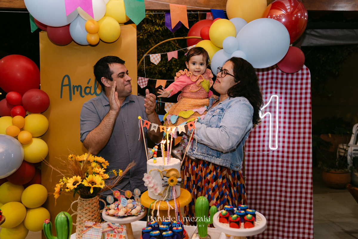 Amália comemorando seu primeiro aniversário em uma delicada festa junina no Quintal Pitangueiras, em Mogi das Cruzes, cercada pela família e amigos.