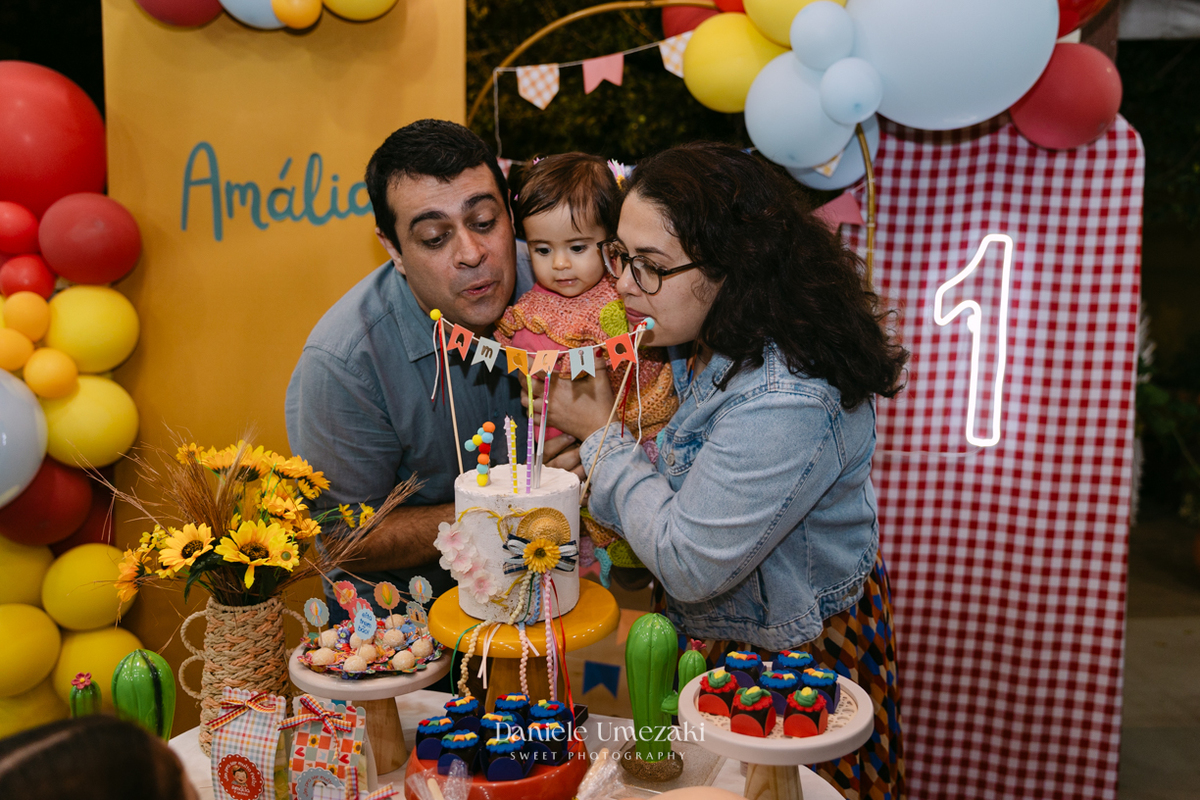 Amália comemorando seu primeiro aniversário em uma delicada festa junina no Quintal Pitangueiras, em Mogi das Cruzes, cercada pela família e amigos.