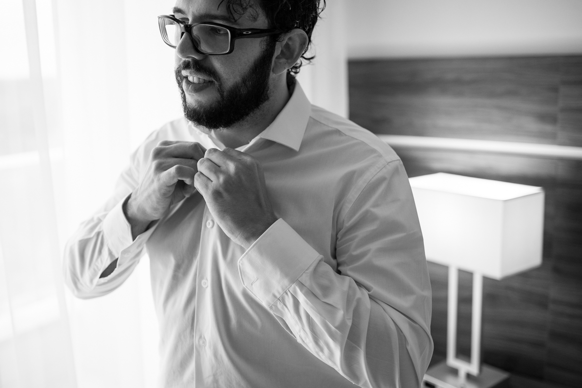 noivo abotoando a camisa no dia do casamento