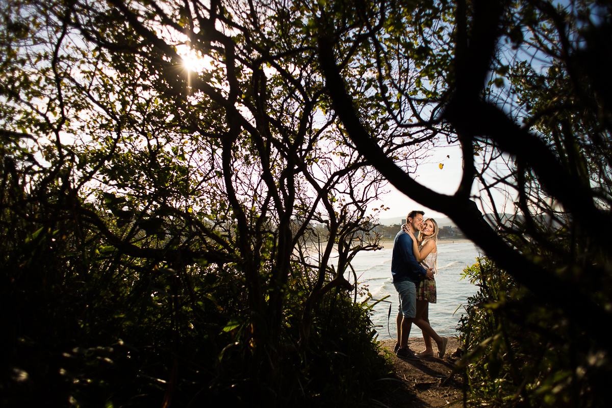 casal se abraçando com praia de bombinhas no fundo