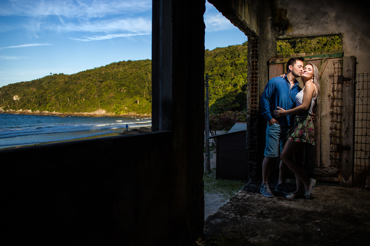 casal junto em casa abandonada e praia de fundo