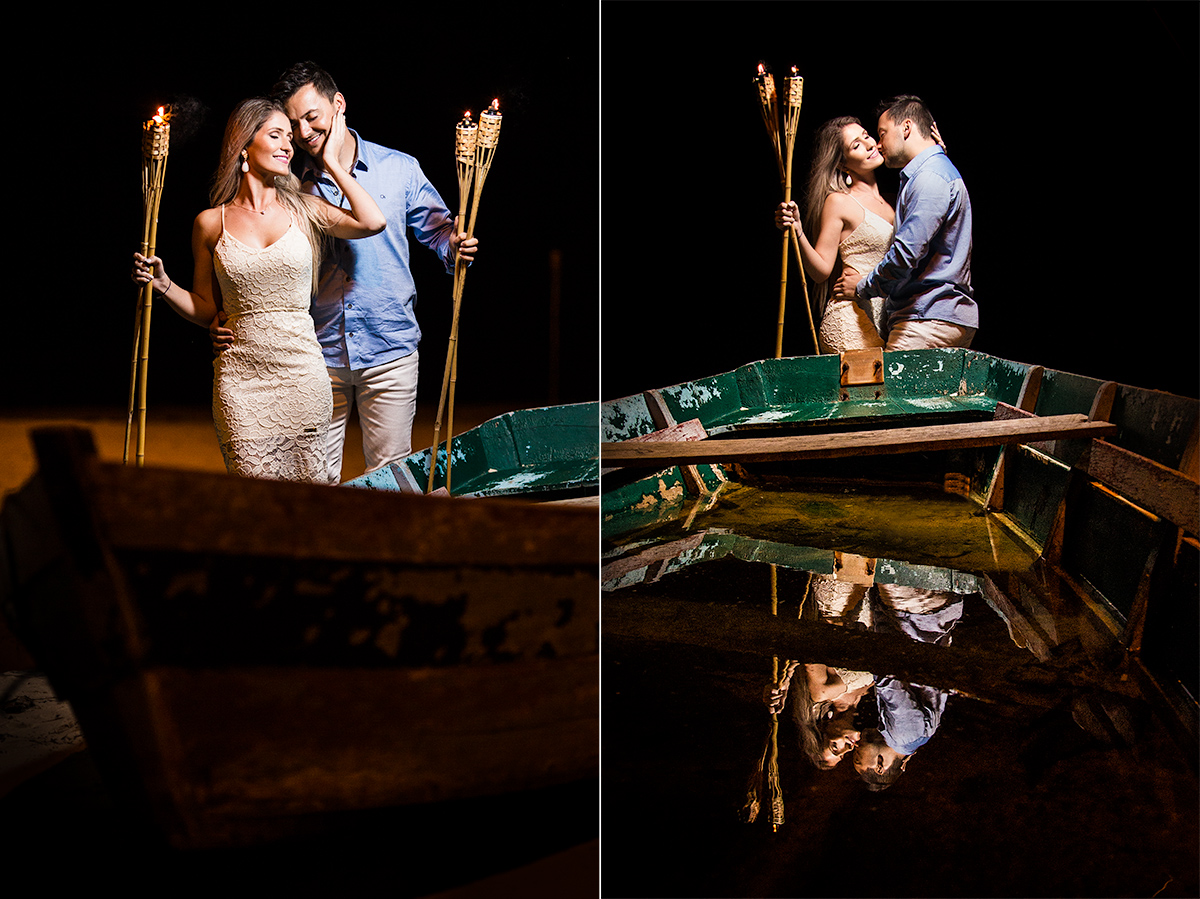 casal segurando tochas de fogo em frente a um barco em bombinhas