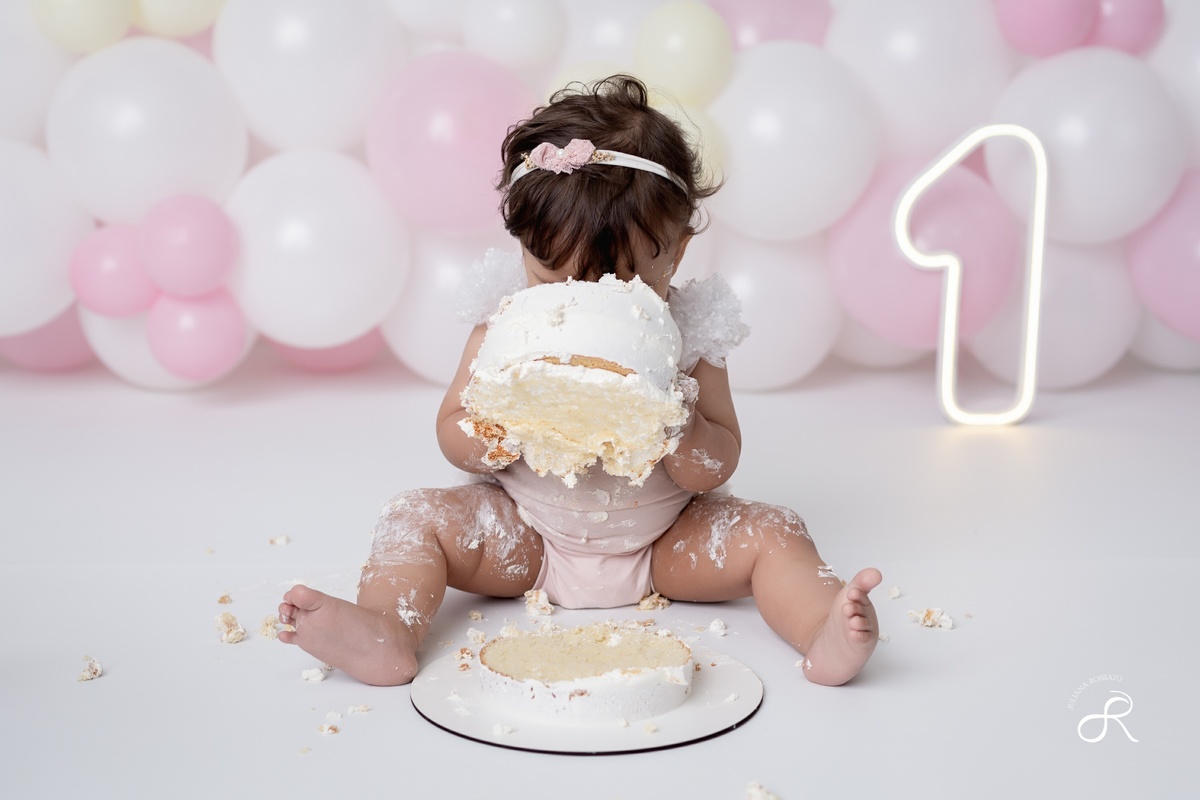 Ensaio smash de 1 ano com bexigas coloridas entre branco, rosa e amarelo e tema clean para comemorar seu primeiro aniversário de forma atemporal.
