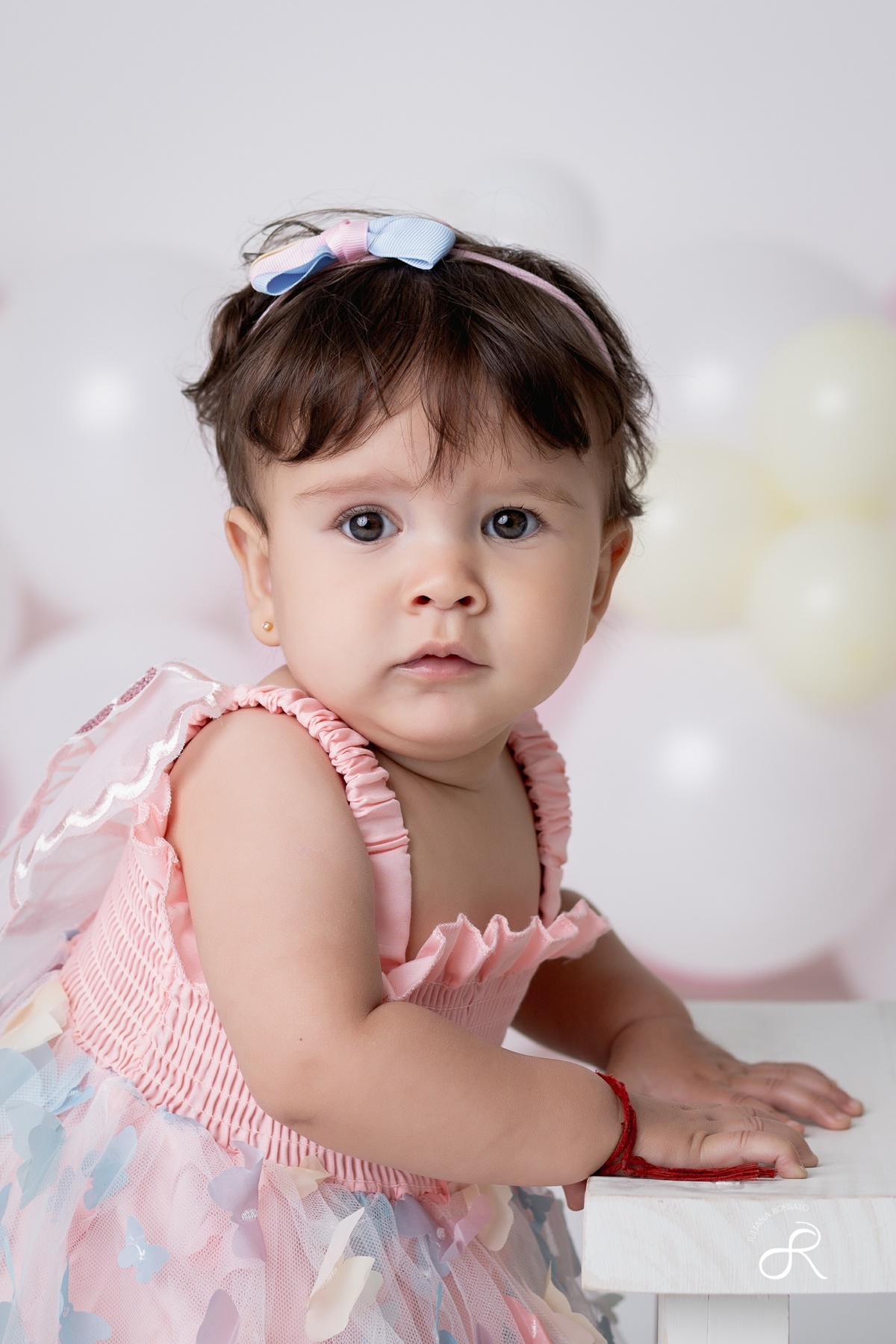 Ensaio smash de 1 ano com bexigas coloridas entre branco, rosa e amarelo e tema clean para comemorar seu primeiro aniversário de forma atemporal.