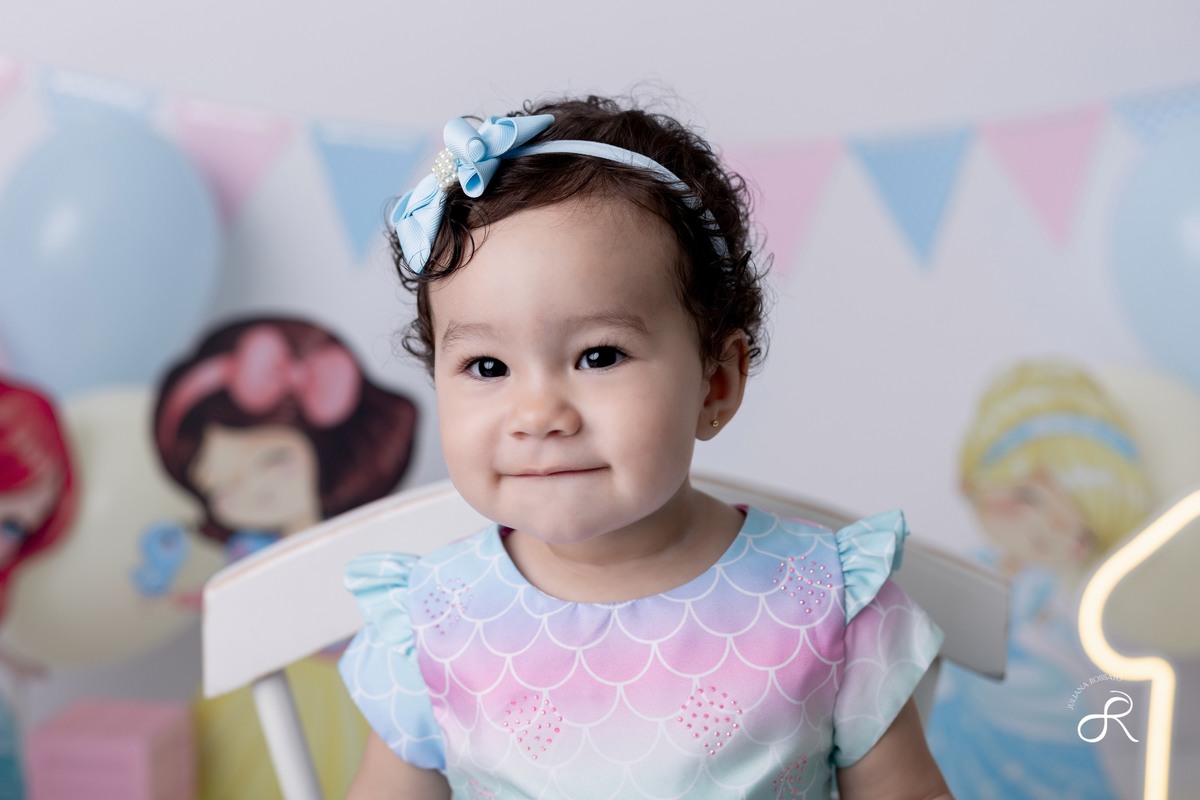 Ensaio smash de 1 ano com bexigas coloridas rosa, amarelo e azul, tema princesas para comemorar seu primeiro aniversário, ariel, branca de neve, cinderela, bela, pequena sereia, ensaio com bolo, ensaio com fruta