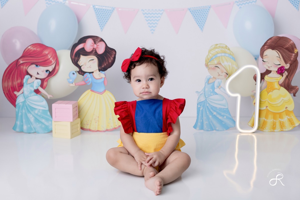 Ensaio smash de 1 ano com bexigas coloridas rosa, amarelo e azul, tema princesas para comemorar seu primeiro aniversário, ariel, branca de neve, cinderela, bela, pequena sereia, ensaio com bolo, ensaio com fruta