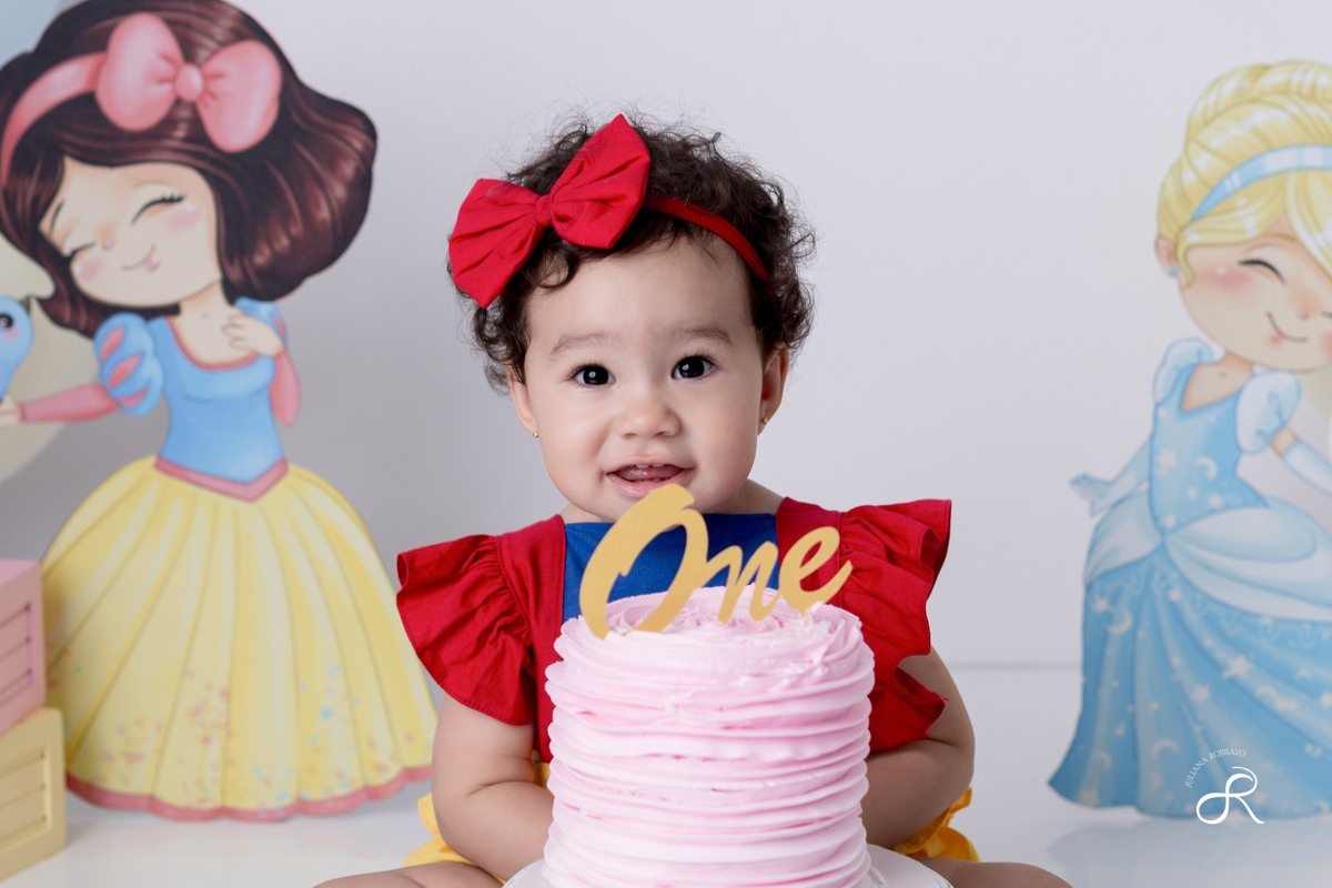 Ensaio smash de 1 ano com bexigas coloridas rosa, amarelo e azul, tema princesas para comemorar seu primeiro aniversário, ariel, branca de neve, cinderela, bela, pequena sereia, ensaio com bolo, ensaio com fruta