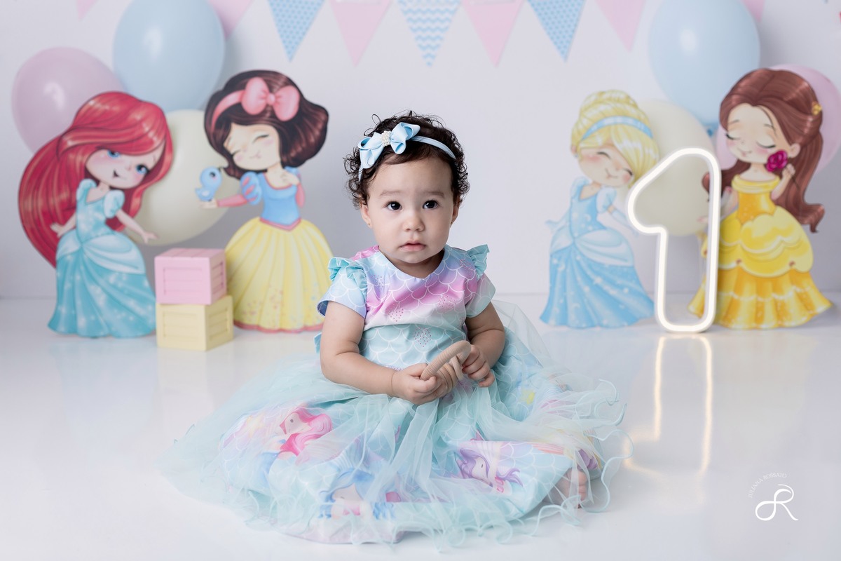 Ensaio smash de 1 ano com bexigas coloridas rosa, amarelo e azul, tema princesas para comemorar seu primeiro aniversário, ariel, branca de neve, cinderela, bela, pequena sereia, ensaio com bolo, ensaio com fruta