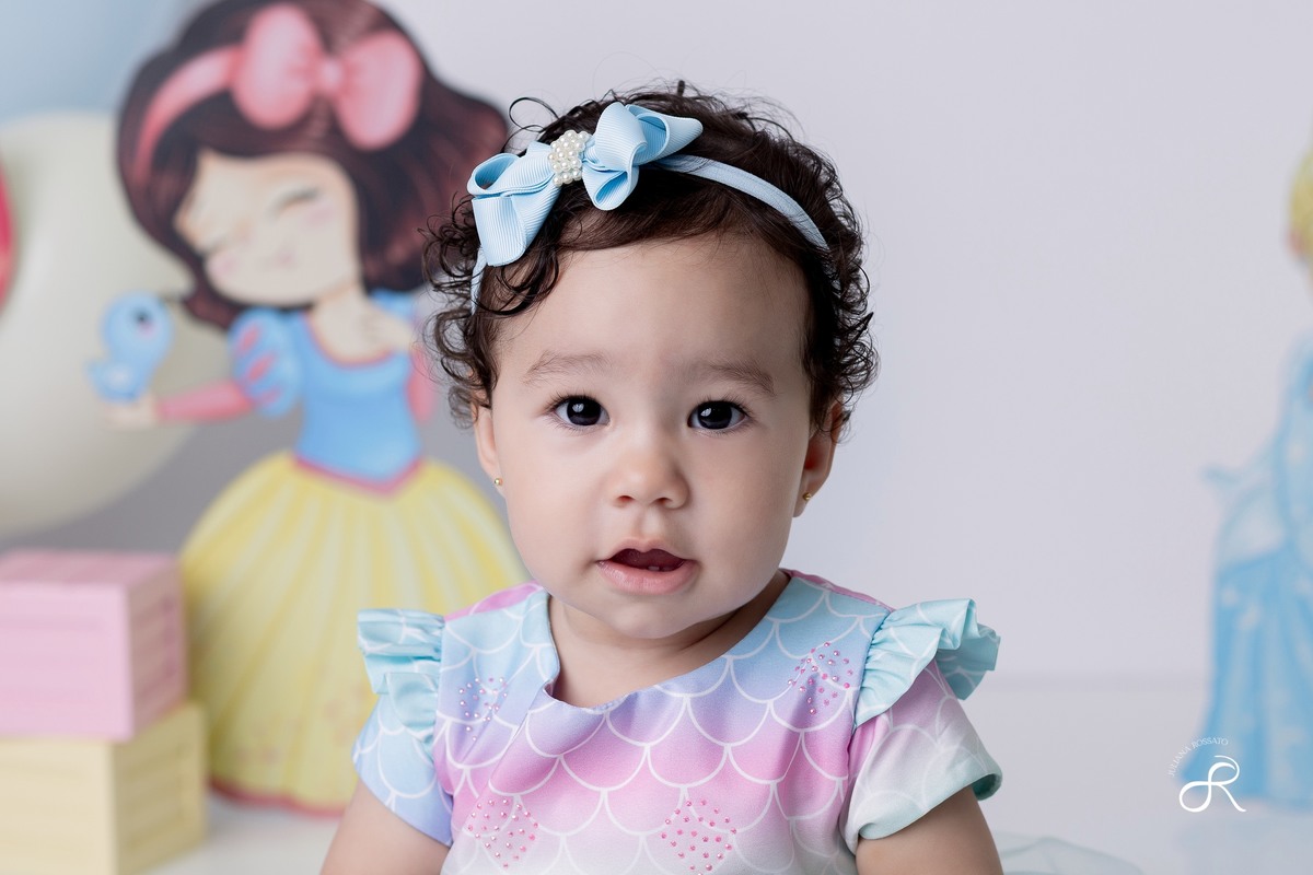 Ensaio smash de 1 ano com bexigas coloridas rosa, amarelo e azul, tema princesas para comemorar seu primeiro aniversário, ariel, branca de neve, cinderela, bela, pequena sereia, ensaio com bolo, ensaio com fruta