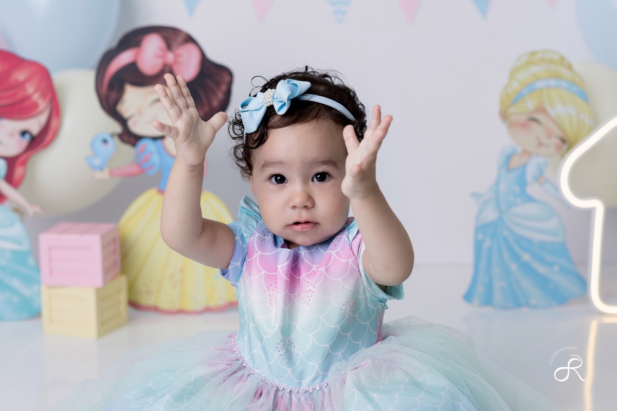 Ensaio smash de 1 ano com bexigas coloridas rosa, amarelo e azul, tema princesas para comemorar seu primeiro aniversário, ariel, branca de neve, cinderela, bela, pequena sereia, ensaio com bolo, ensaio com fruta