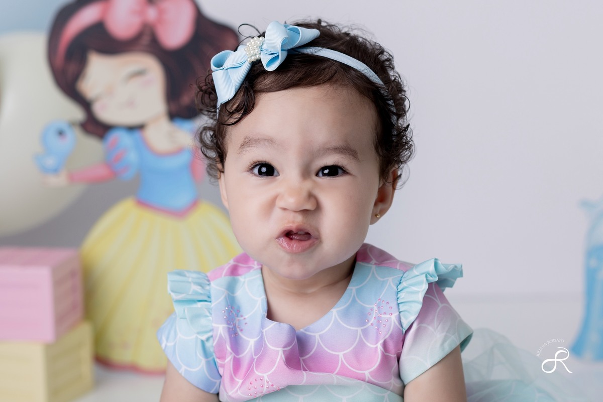 Ensaio smash de 1 ano com bexigas coloridas rosa, amarelo e azul, tema princesas para comemorar seu primeiro aniversário, ariel, branca de neve, cinderela, bela, pequena sereia, ensaio com bolo, ensaio com fruta