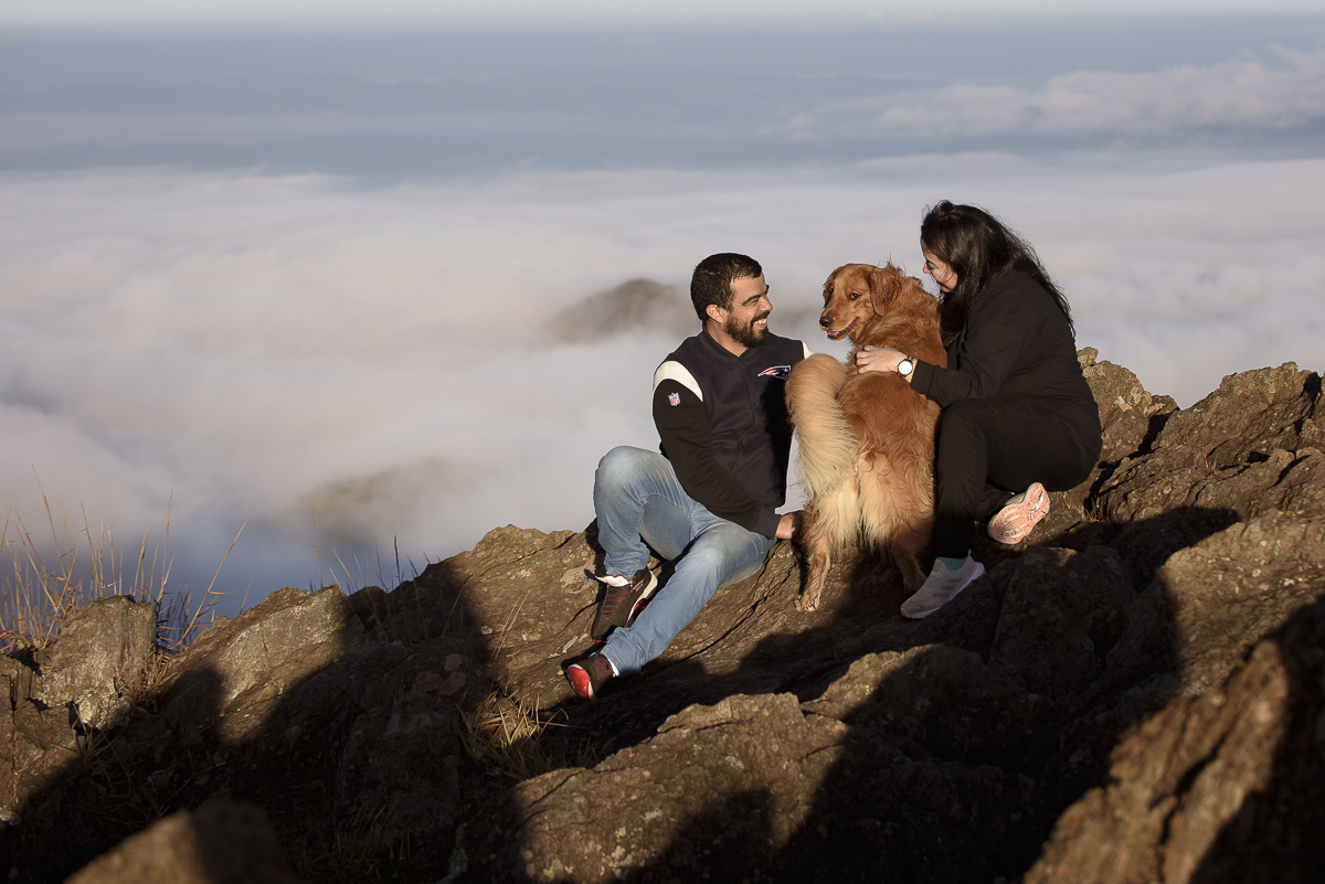 foto aberta do casal olhando para seu golden retriver e ao fundos nuven baixas  de uma manhã fria 