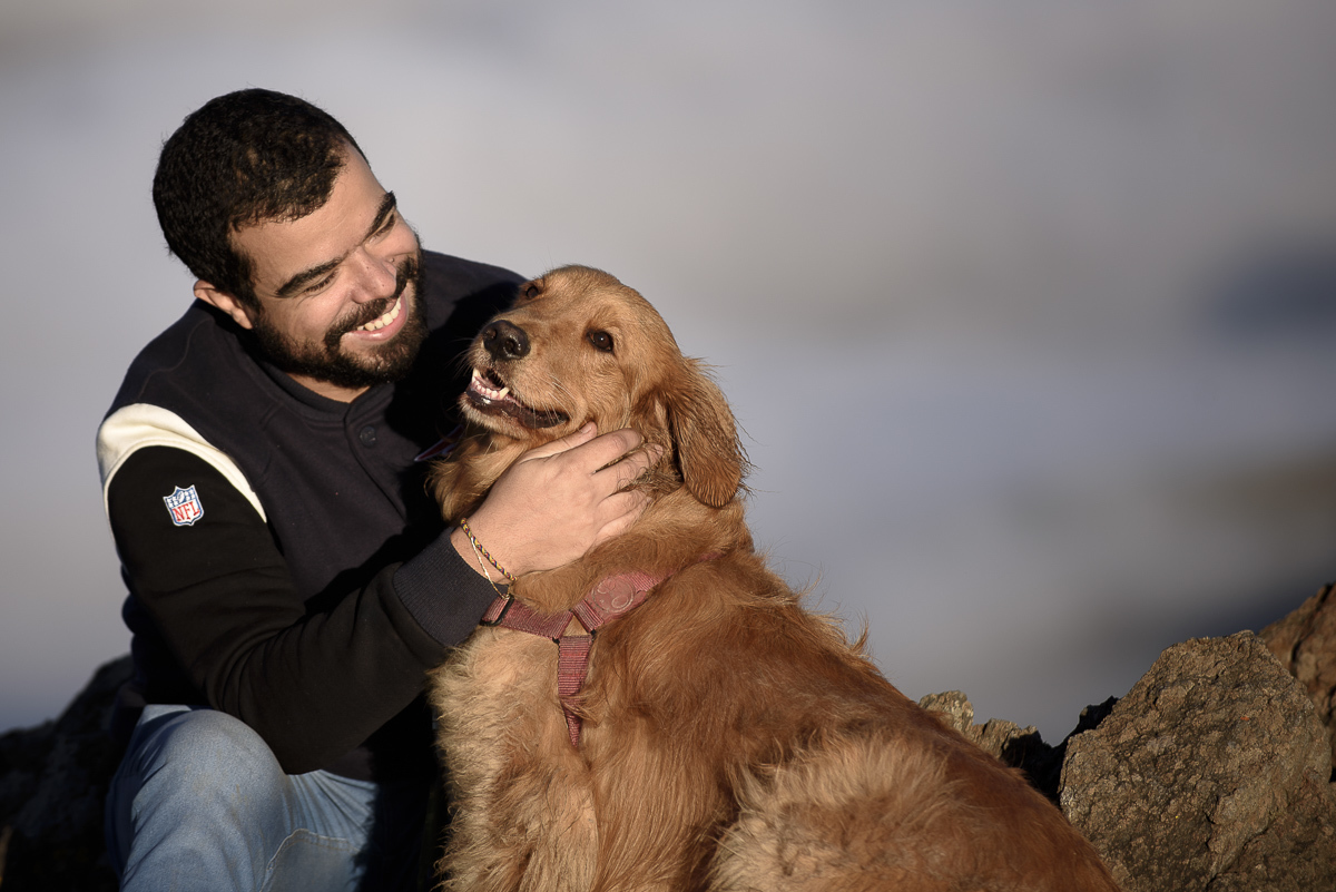 homem tocando rosto do seu golden retriever e sorrindo