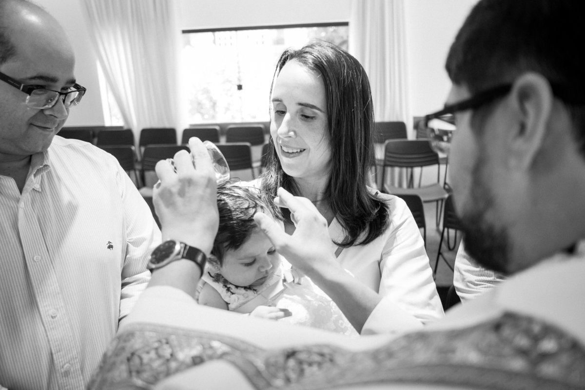 Padre derramando água na cabeça do bebê