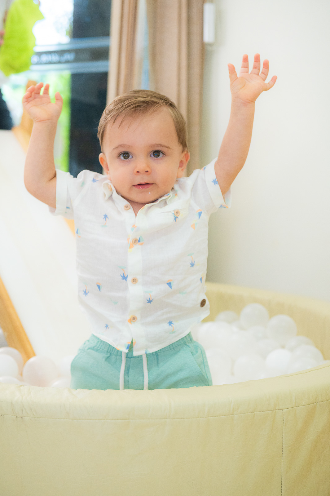 bebê olhando pra câmera com as mãos pra cima