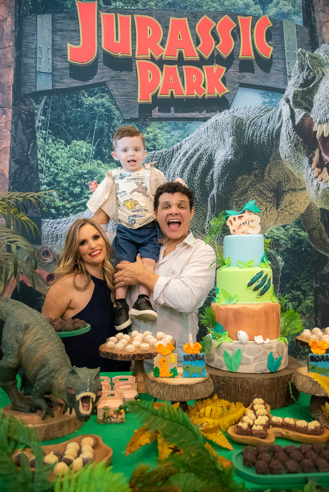 mãe  e pai segurando o filho ao lado do bolo