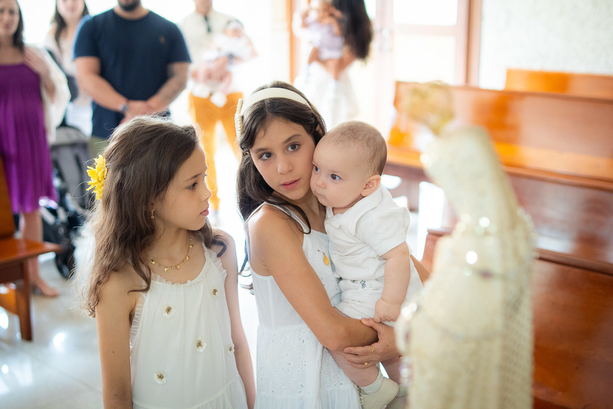 as duas irmãs segurando o bebê