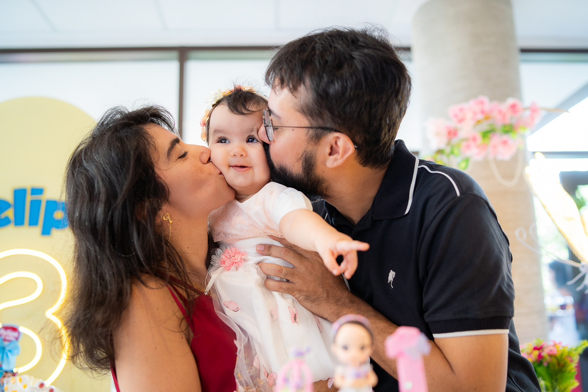 pais beijando na bochecha  da bebê