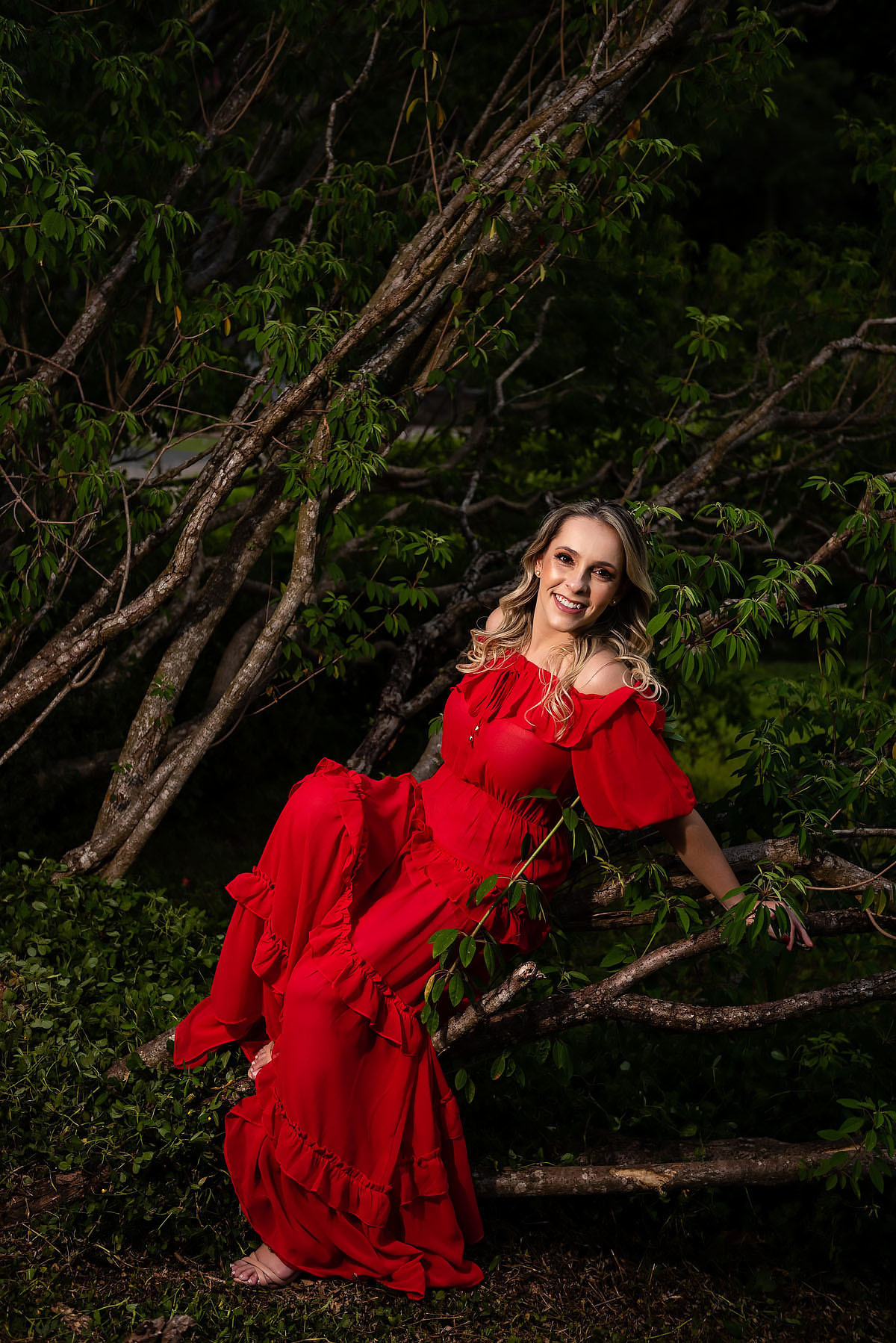 mulher posa de vermelho entre os galhos