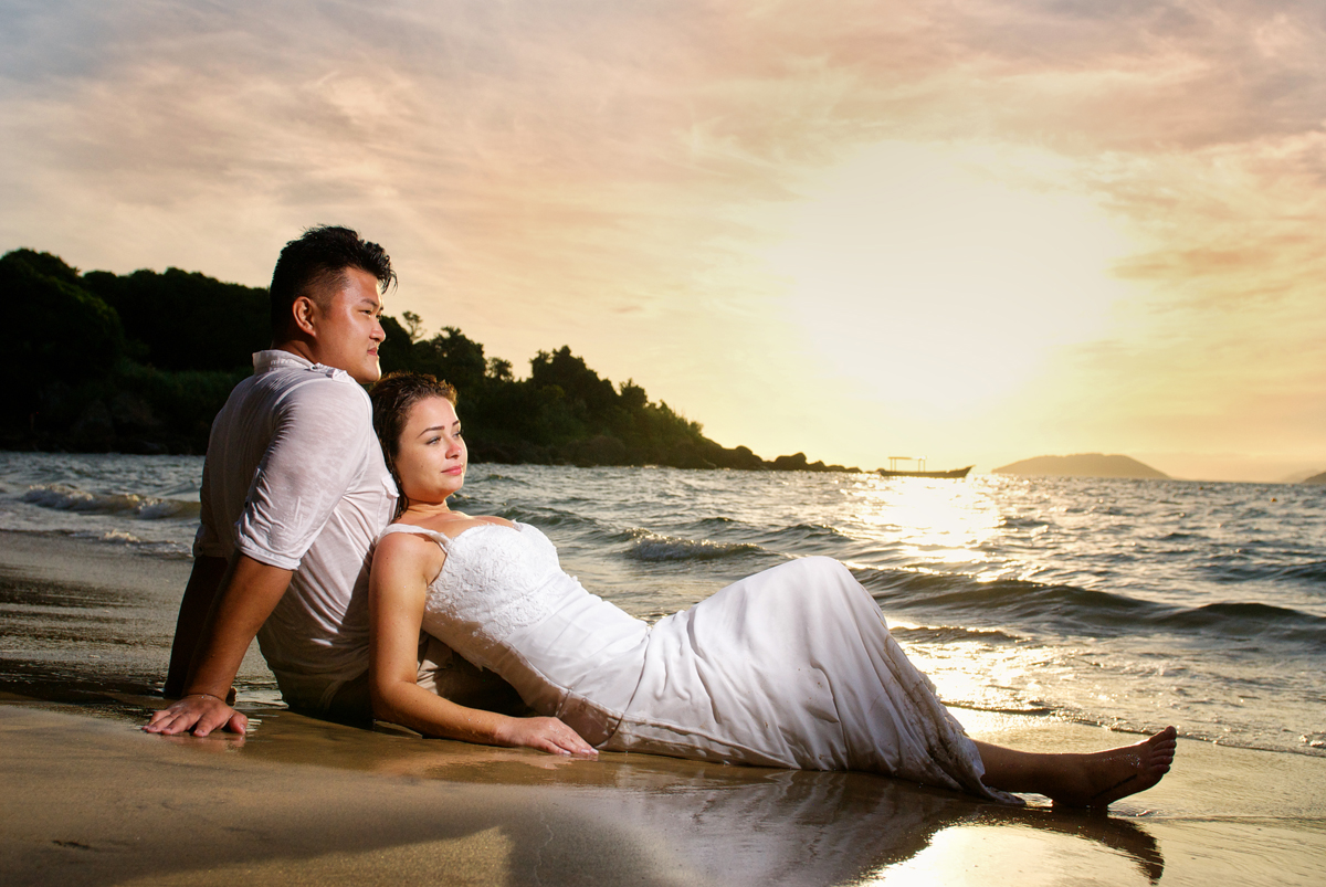 noivos descansam na praia ao por do sol