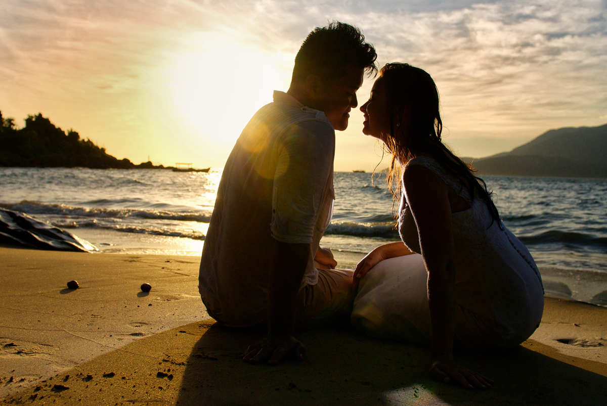 noivos se beijam na praia no por do sol