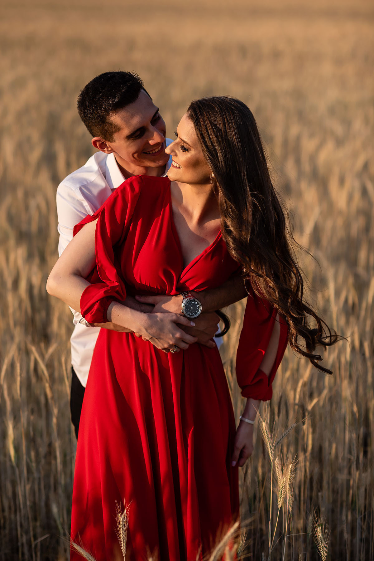 casal pousa para foto em campo de trigo