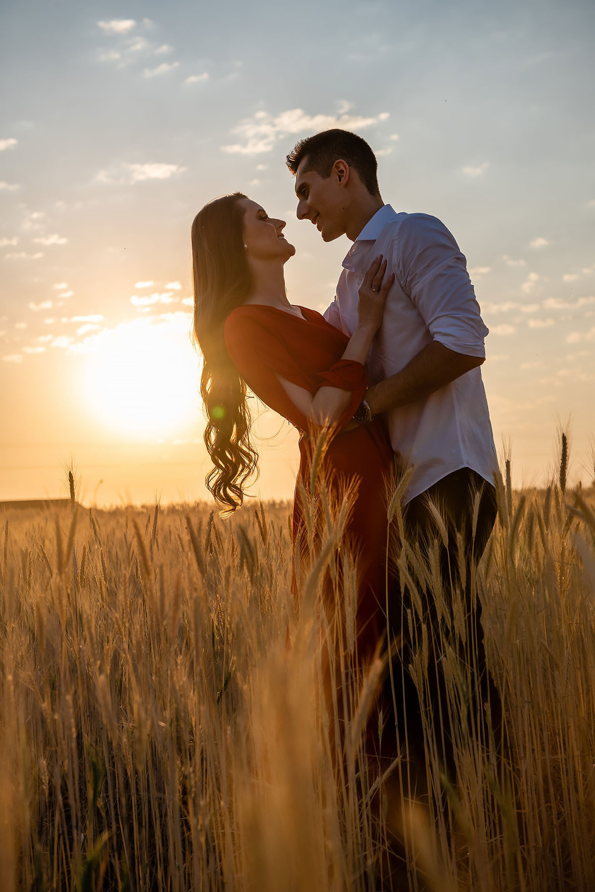 casal se beija ao por do sol em campo de trigo