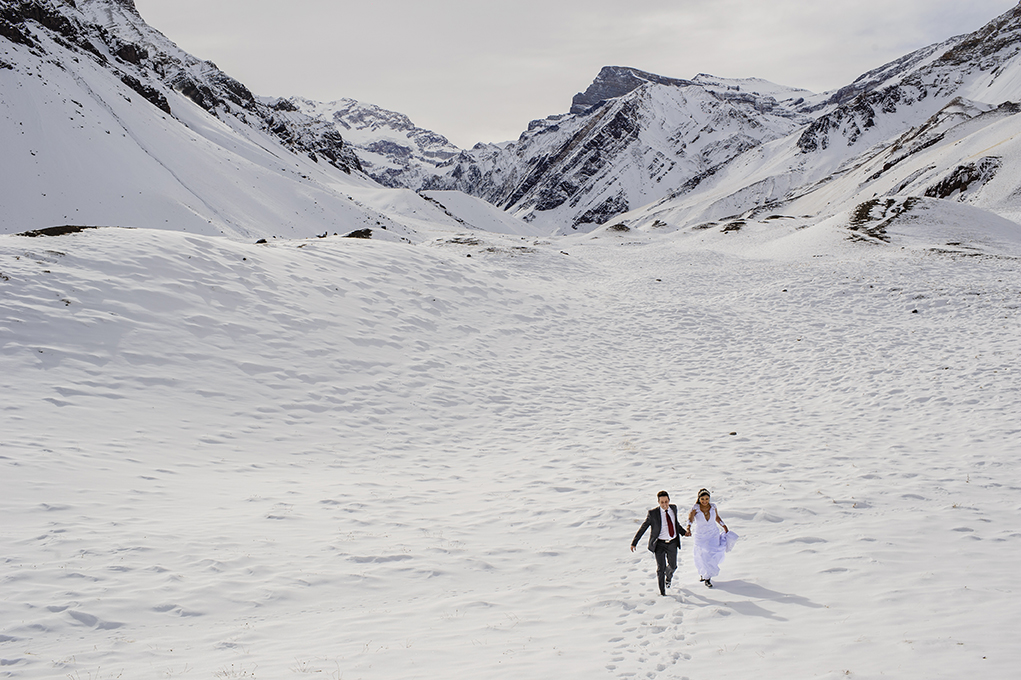 Noivos correndo na neve dos andes