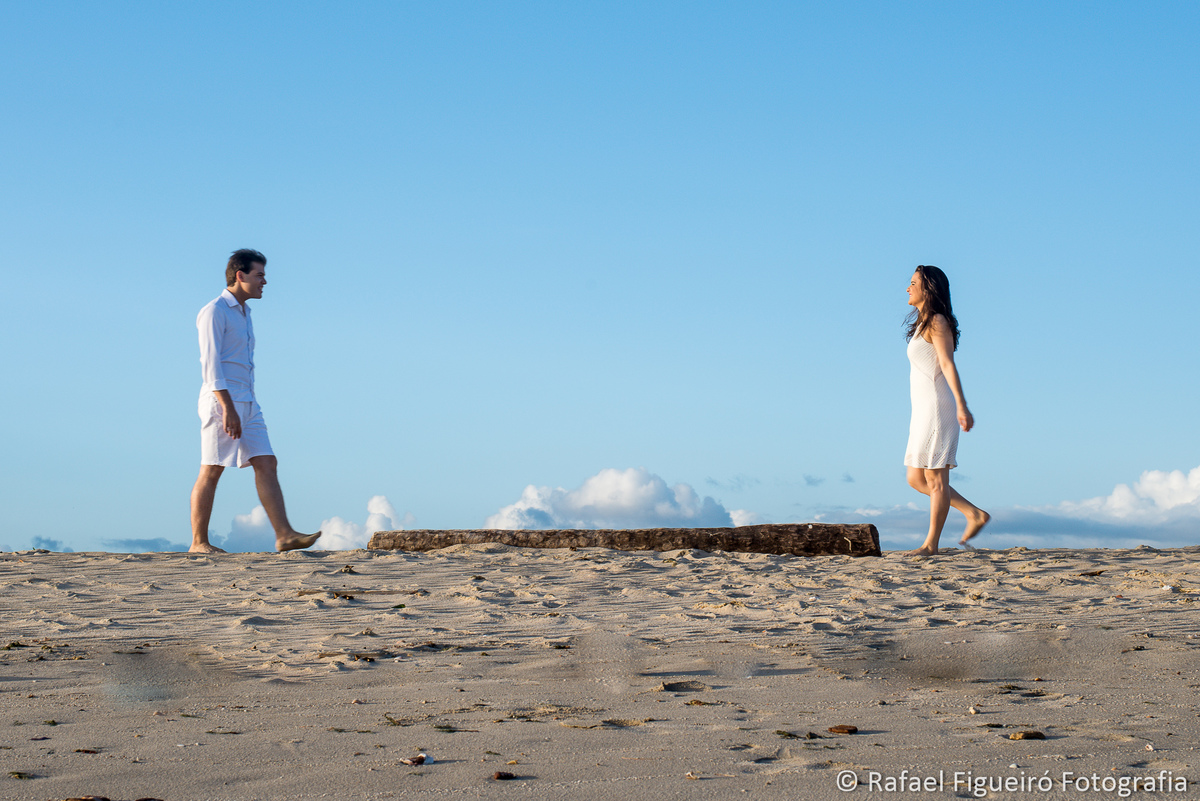 casal caminhando areia praia tronco coqueiro céu azul