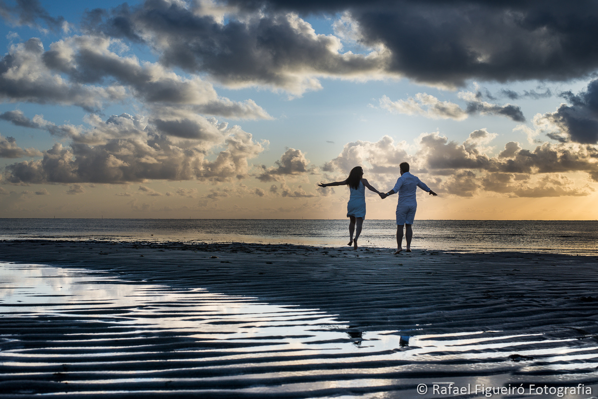 casal correndo de maos dadas braços abertos aviaozinho praia nascer do sol maria farinha pe