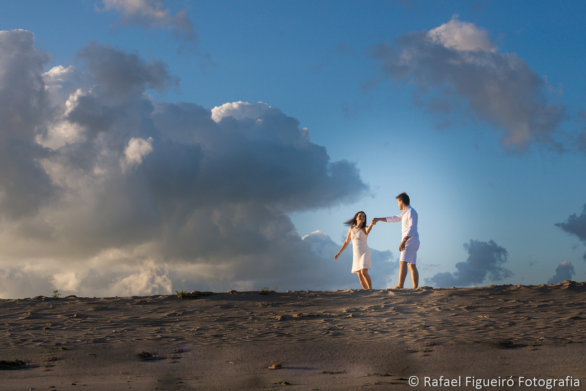 casal dançando na areia praia luz sol amarelada ceu azul com nuvens