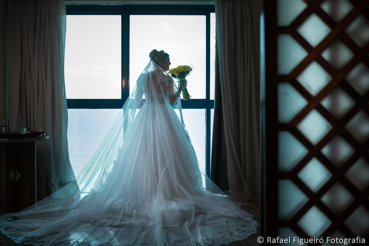 noiva em frente a janela com bouquet amarelo na mao luz linda mar
