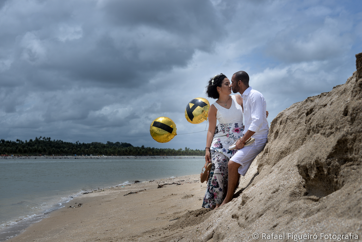 casal encostado no barranco de areia namorando rio timbó maria farinha ceu nuvens baloes amarelos