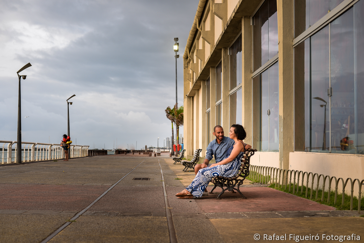 casal sentado banco de madeira vidros reflexo céu recife antigo