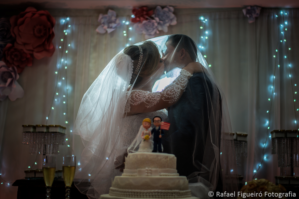 beijo dos noivos no bolo sob o veu debaixo do veu contra luz aceso