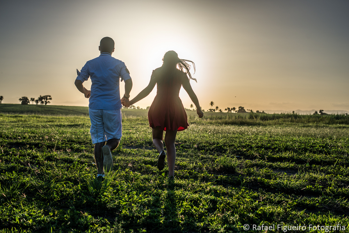 casal correndo no campo gramado por do sol, contra luz feliz casa de campo
