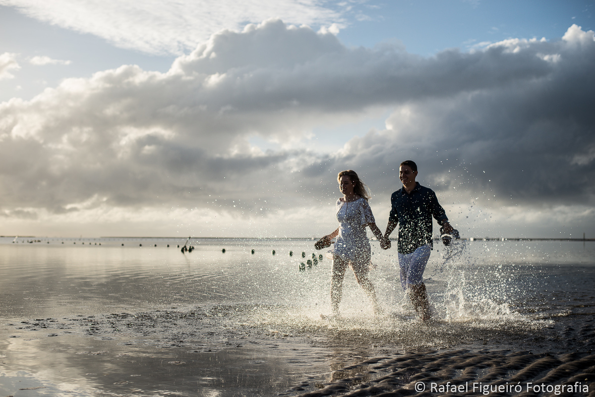 casal correndo agua respingando contra luz carneiros pe